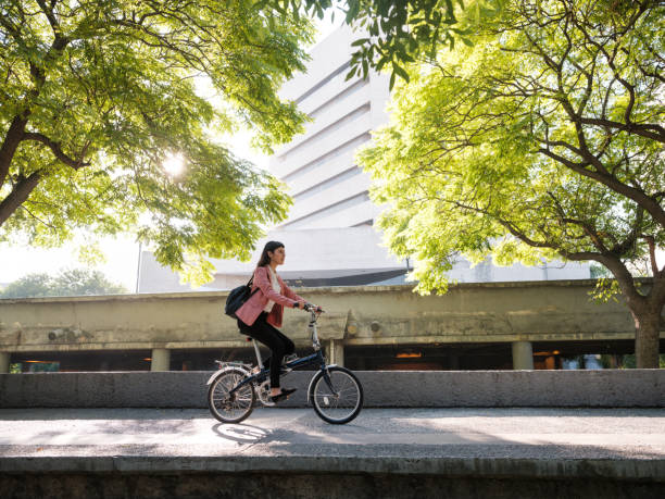 junge frau geht mit dem fahrrad zur arbeit - mobility stock-fotos und bilder