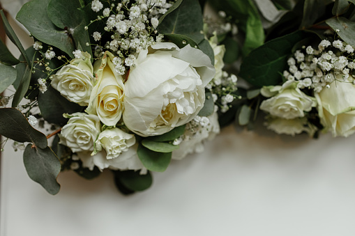 wedding bouquets of white roses and greens for bridesmaids on a white table. brides morning. wedding accessories. selective focus.