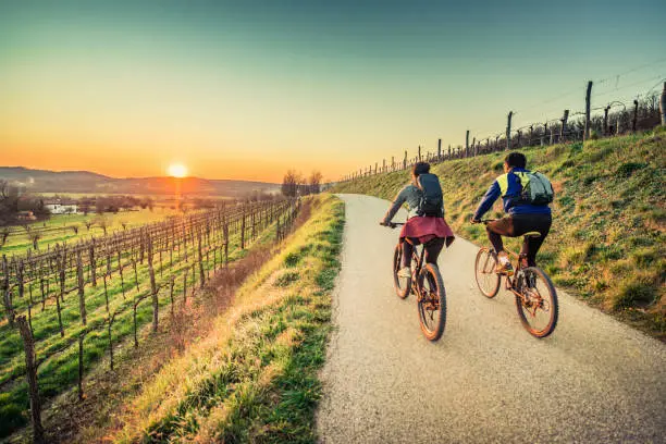 Biker couple riding moutain bike in the countryside at sunset