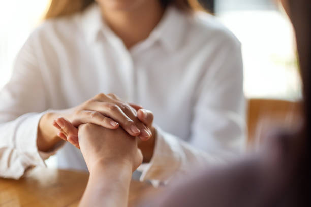 istock Women holding each other hands for comfort 1215623894