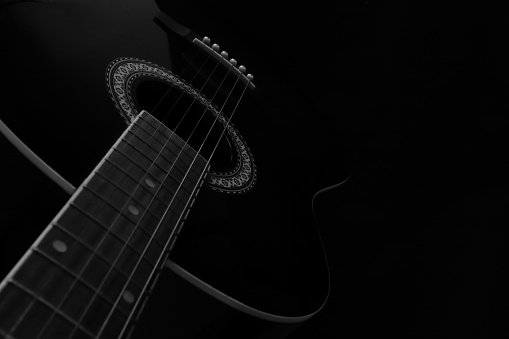 Guitar neck with the strings and fret board in close up in black and white