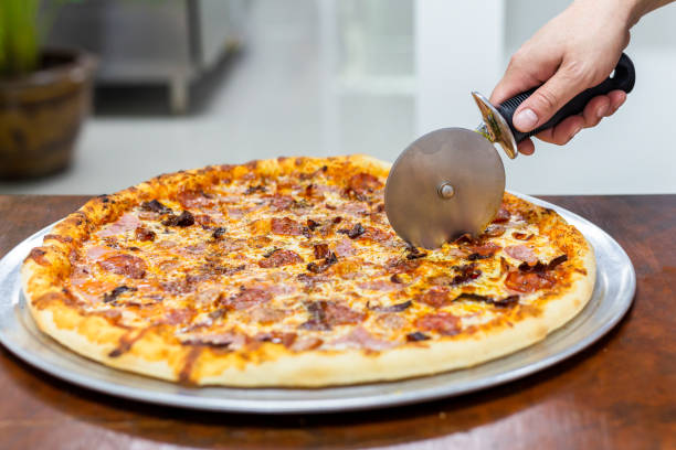 istock Closeup hand of chef cutting pizza on table. 1215636764