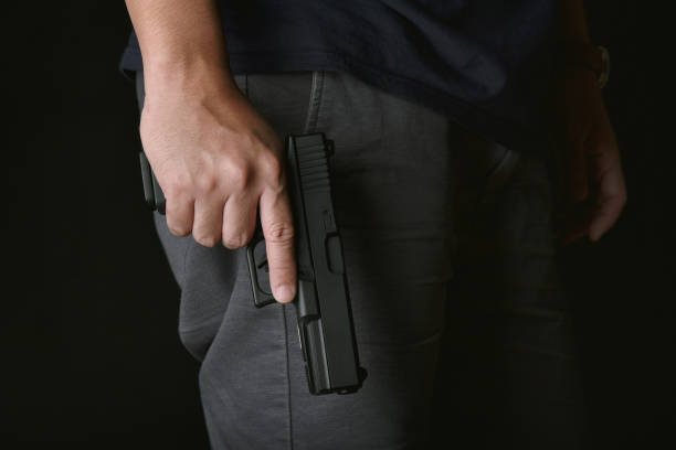 Man holding gun close to the body, Killer with 9mm handgun pistol waiting for robbing the victim, Weapon and violence crime concept.A Man holding gun close to the body, Killer with 9mm handgun pistol waiting for robbing the victim, Weapon and violence crime concept.A gunman photos stock pictures, royalty-free photos & images