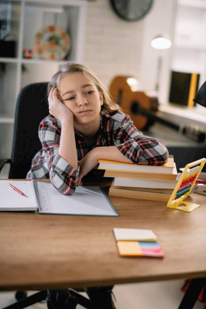 istock Tired little girl doing homework at her desk. 1215639839