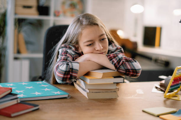 istock Tired little girl doing homework. 1215639845