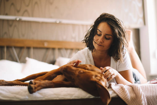 istock Beautiful woman lying on bed with her dog 1215640806