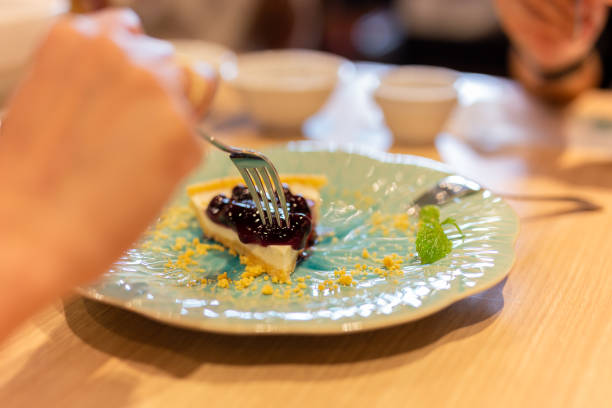 istock Woman hands with fork eating blueberry cheese cake in restaurant. 1215640840