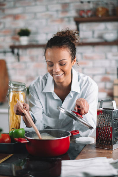 istock Young woman in kitchen preparing pasta 1215641032