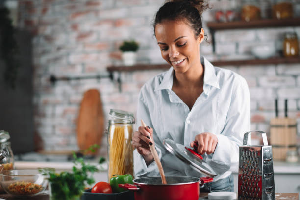istock Young woman in kitchen preparing pasta 1215641071