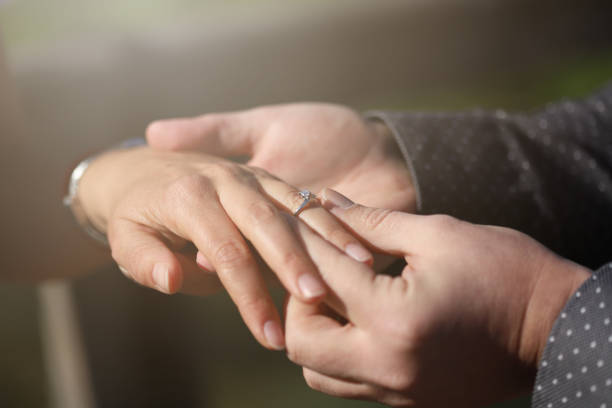 istock Female and male hands slipping on engagment ring 1215641821