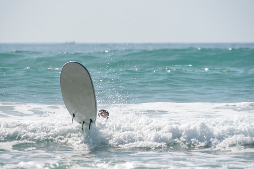 Young man in the surf on Taghazout beach, Morocco. This a from a motordrive series of a lesson where he gets onto the board and then overbalances. the sequence starts with him crouched on the board and ends with him overbalancing backwards off the board.