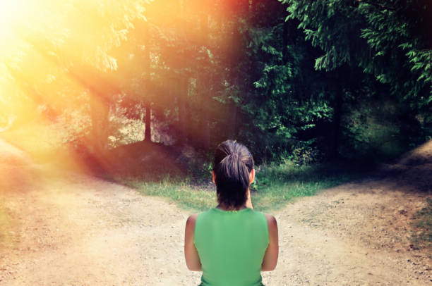 ragazza con una scelta vicino alla strada biforcata. il concetto di soluzione: il percorso verso il successo e il percorso di rischio - footpath field nature contemplation foto e immagini stock