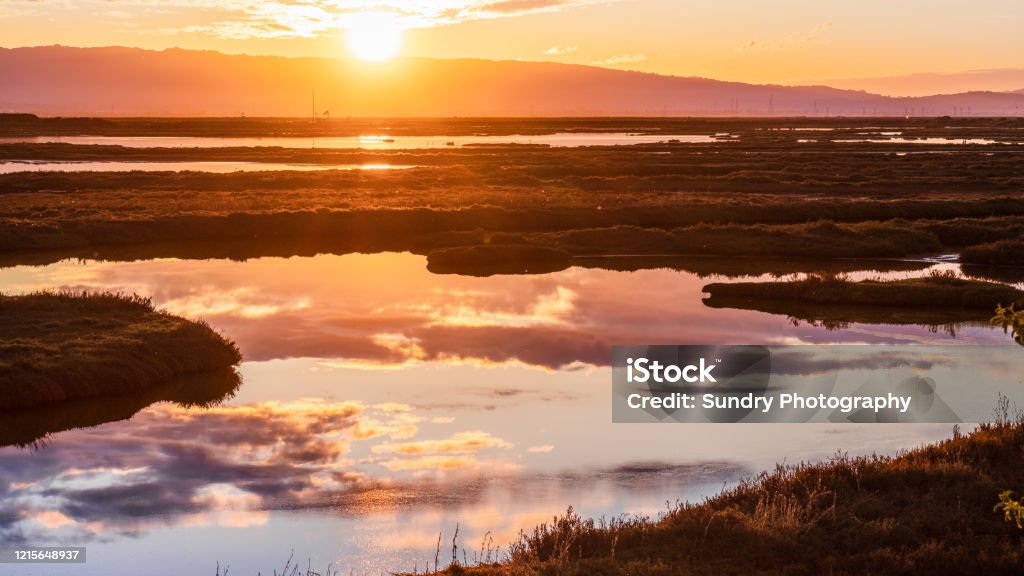 Sunset views of the tidal marshes of Alviso with colorful clouds reflected on the calm water surface, Don Edwards San Francisco Bay National Wildlife Refuge, San Jose, California California Stock Photo