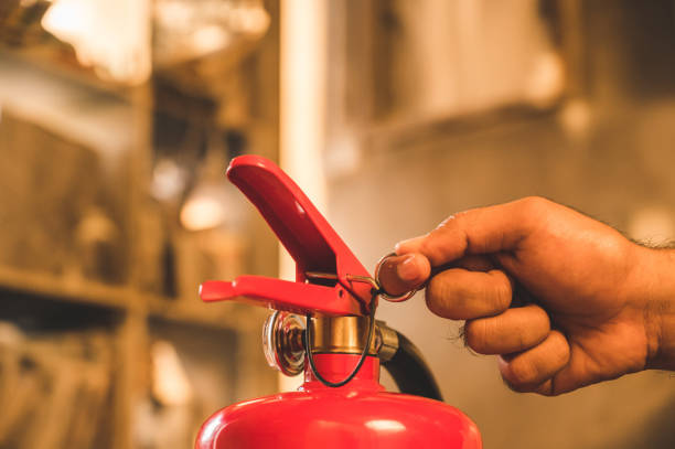 istock Close up hand Fireman using fire extinguisher fighting. Hand pulling pin of fire extinguisher 1215651381