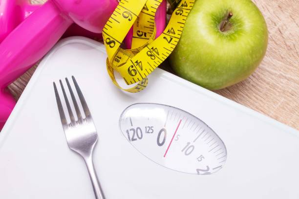 istock scale with measuring tape and fruit, diet and weight loss concept 1215652126