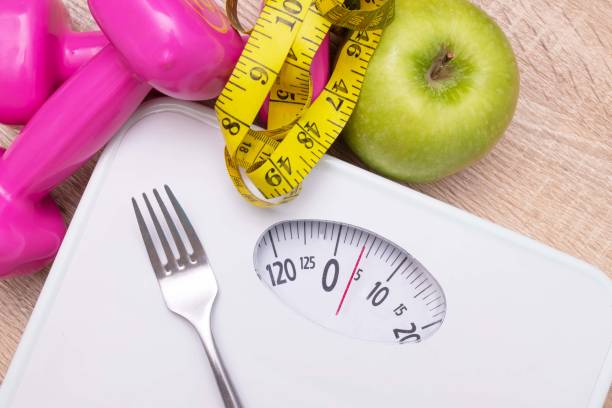 istock scale with measuring tape and fruit, diet and weight loss concept 1215652263