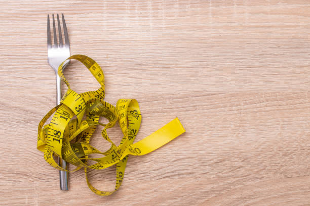istock fork with tape measure, diet and weight loss concept 1215657152