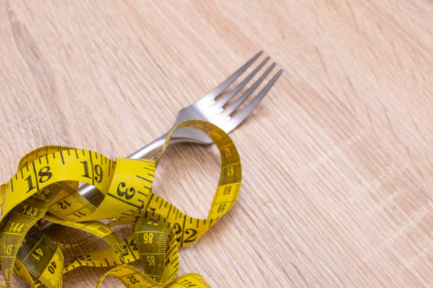 istock fork with tape measure, diet and weight loss concept 1215657184
