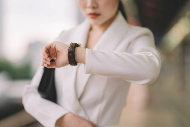 une jeune femme d’affaires chinoise asiatique en mouvement dans la gare monorail attendant le train et regardant son heure de contrôle de quart de la journée - checking the time watch women looking photos et images de collection