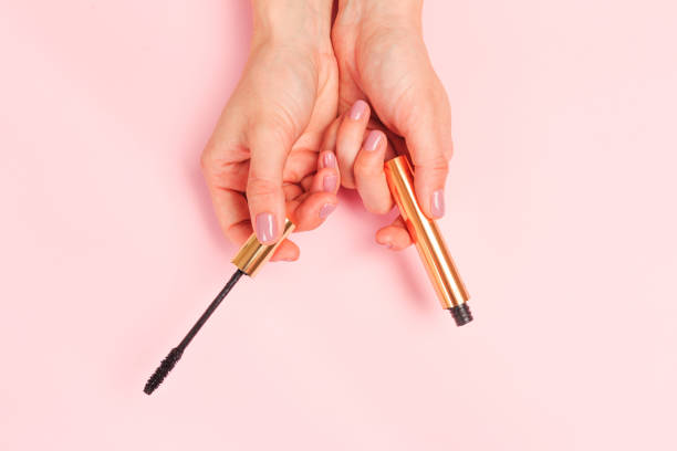 Beautiful young woman's hands holding  mascara on pastel pink background - Image