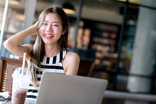 lifestyle attractive asian female casual dress relax work with laptop smartphone freelance career smile with happiness and confident at coffeeshop with blur background