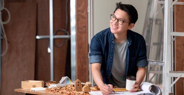 istock asian attractive glasses interior designer working at house site renovation construction progress with smile and confident at desk with blue print and drawing tool 1215665788