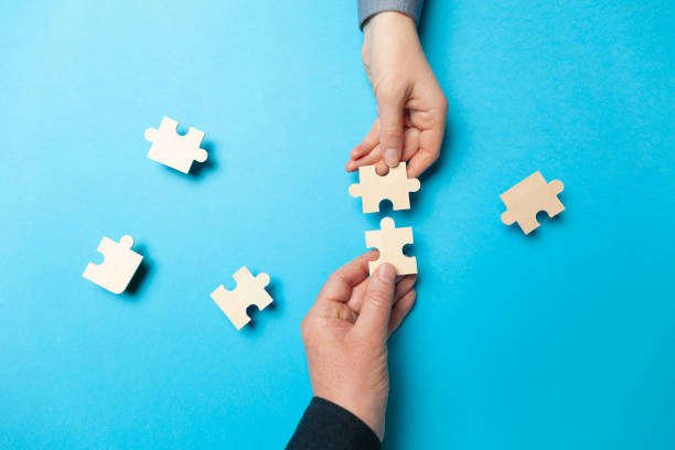 istock Two hands connect puzzles on a blue background. Cooperation and teamwork in business. Collaboration people for success 1215666947