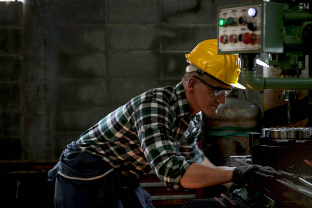 istock Industrial engineer worker wearing helmet and safe glasses  operating with machinery at manufacturing plant factory, working with machine in industry concept 1215668016