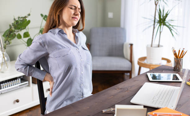 Freelancer young woman suffering with back pain Freelancer young woman suffering with back pain while working in her office at home backache photos stock pictures, royalty-free photos & images