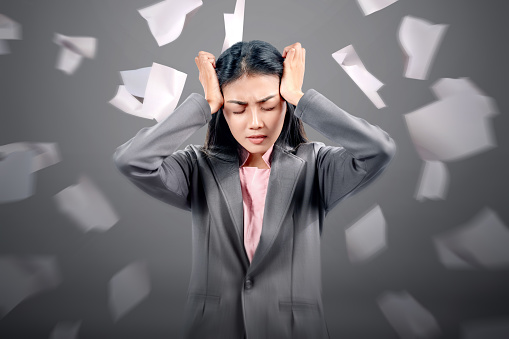 Asian businesswoman with headache expression with flying paper background
