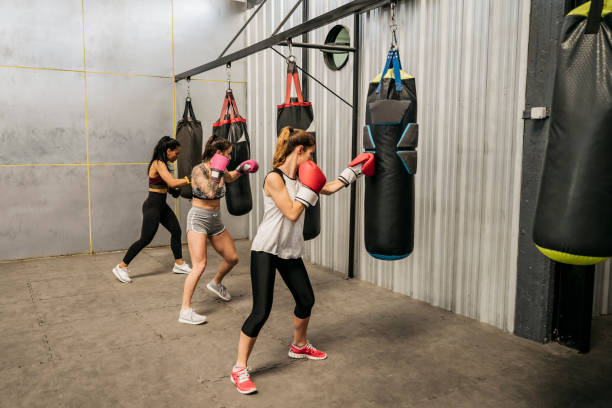 jeunes boxeurs féminins s’enagant avec des sacs lourds à la gymnastique - boxing womens photos et images de collection