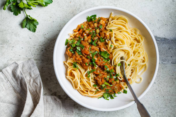 Vegetarian lentils bolognese pasta with parsley in white dish, top view. Healthy vegan food concept. Vegetarian lentils bolognese pasta with parsley in a white dish. Healthy vegan food concept. bolognese sauce photos stock pictures, royalty-free photos & images