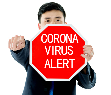 Young businessman holding stop sign with coronavirus alert.