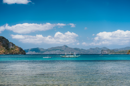 Filippino boats in open ocean in El Nido bay. Islands shapes in background. Palawan island, Philippines.