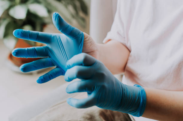 una mujer china asiática usando sus guantes quirúrgicos de látex en casa antes del proceso de limpieza - guante quirúrgico fotografías e imágenes de stock