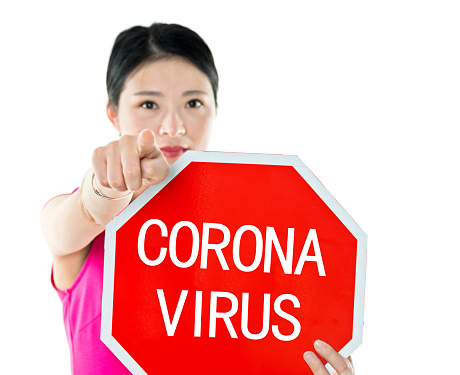 Young woman holding stop sign with coronavirus.