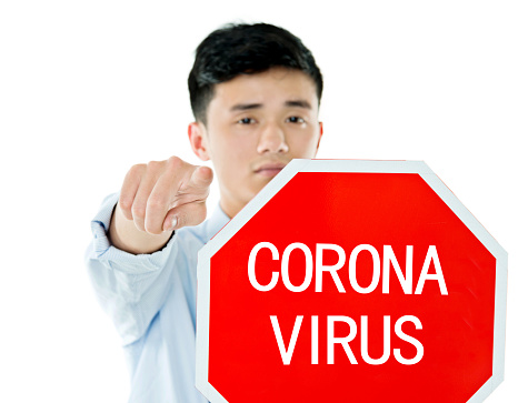 Young businessman holding stop sign with coronavirus.