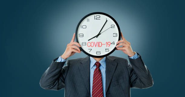 istock Businessman holding clock with word COVID-19 1215675178