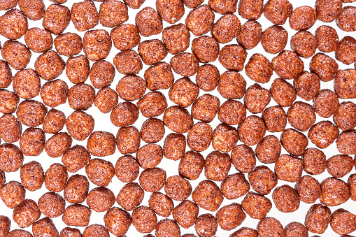 Close up top view of chocolate balls in milk. Fast breakfast for children. Corn balls background.