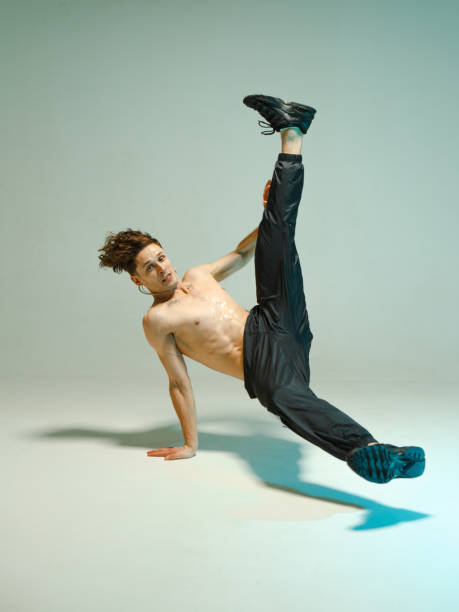 istock A young graceful guy is dancing a break dance on the floor without a t-shirt. Complex tricks. Body with tattoos. 1215678344
