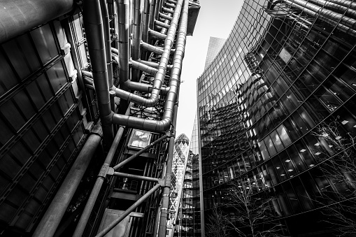 Wide angle image depicting an abstract view looking up at various different modern buildings and futuristic skyscrapers in central London, UK. It is an urban jungle comprised of glass and steel, leading lines and abstract geometric shapes.