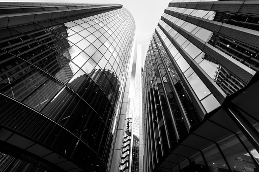 Wide angle image depicting an abstract view looking up at various different modern buildings and futuristic skyscrapers in central London, UK. It is an urban jungle comprised of glass and steel, leading lines and abstract geometric shapes.