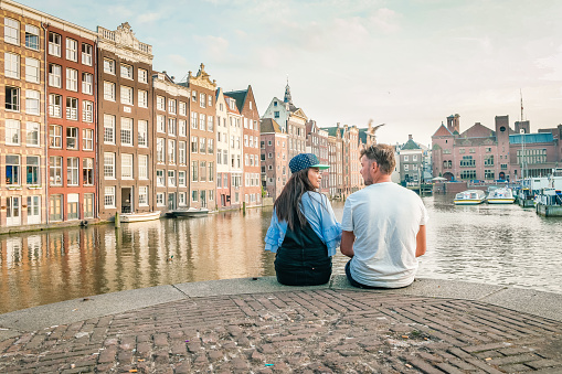 Amsterdam Damrak during sunset, happy couple man and woman on a summer evening at the canals Amsterdam