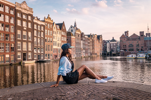 Amsterdam Damrak during sunset, happy woman on a summer evening at the canals Amsterdam