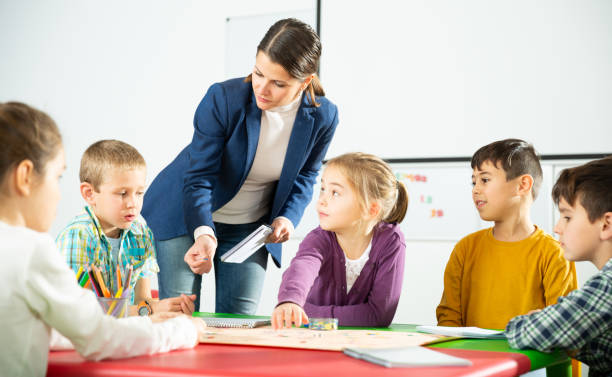 istock Teacher and happy schoolkids playing board game 1215682518
