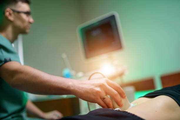 A young male doctor makes a patient an ultrasound of the abdominal cavity. A young male doctor makes a patient an ultrasound of the abdominal cavity. Ultrasound scanner in the hands of a doctor. scientific imaging technique stock pictures, royalty-free photos & images