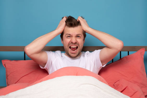 istock Stressed handsome young man sitting in the bed alone feeling unhappy and tired. 1215684603