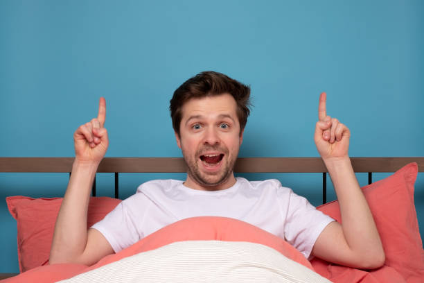 istock Caucasian man resting in bed on quarantine pointing up 1215684624