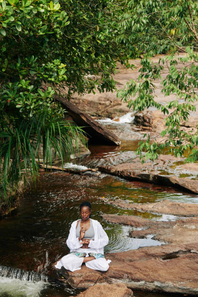 frau meditiert durch plätschernden bach - nature zen like stream water stock-fotos und bilder