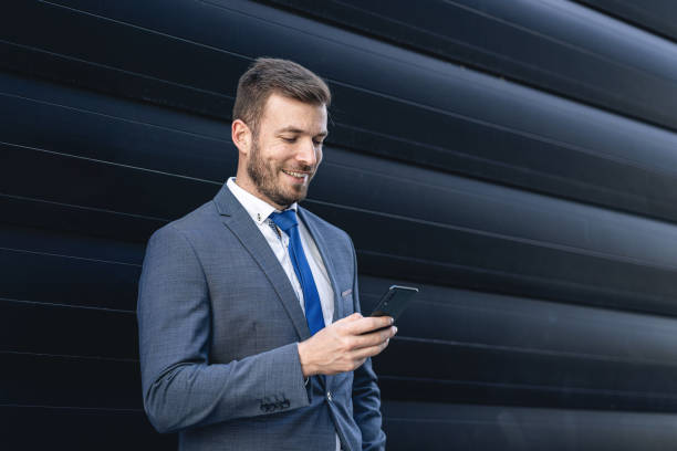istock Handsome smiling businessman text messaging on a mobile phone 1215688072